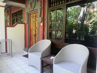 two chairs and a table in front of a window at Dewa Bharata Bungalows Legian in Legian