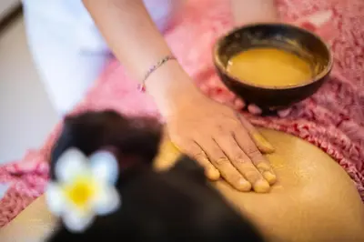 a woman sitting on her back with a bowl of liquid at Rama Residence Seminyak in Seminyak