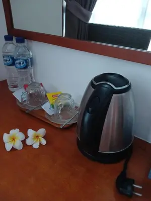 a tea kettle and two flowers on a counter at Pudak Sari Unizou Hostel in Kuta