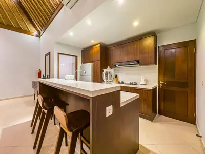 a kitchen with wooden cabinets and a counter with stools at Villa Bugis Seminyak in Seminyak