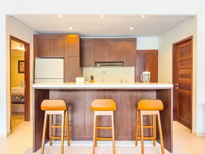 a kitchen with wooden cabinets and a counter with stools at Villa Bugis Seminyak in Seminyak