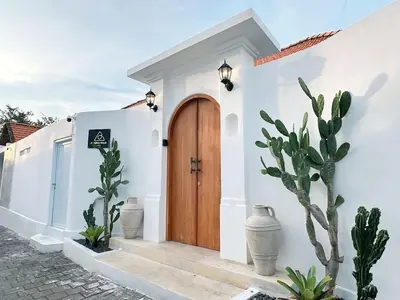 a white house with a wooden door and cactus at Amerta Villa Seminyak in Seminyak