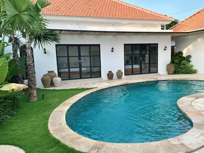 a swimming pool in front of a house at Amerta Villa Seminyak in Seminyak