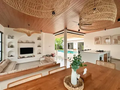 a living room with a wooden ceiling and a dining table at Amerta Villa Seminyak in Seminyak