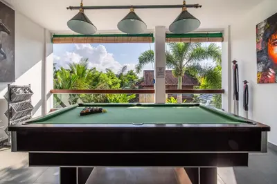 a pool table in a room with a window at Villa Wiana by Villa Finder in Seminyak