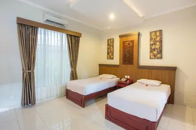 a hotel room with two beds and a window at Hotel Sinar Bali Legian in Legian