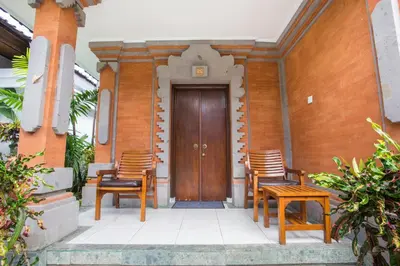a pair of chairs and a wooden door on a house at Hotel Sinar Bali Legian in Legian