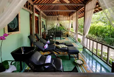 a screened in porch with chairs and a table at Bali Garden Beach Resort in Kuta