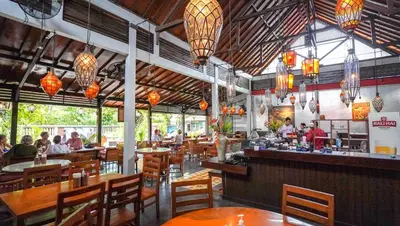 a restaurant with people sitting at tables and a bar at Bali Garden Beach Resort in Kuta