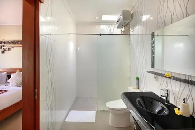 a bathroom with a shower and a toilet and a sink at Kae Villa Anggrek in Seminyak