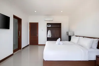 a bedroom with a large white bed and a television at Daha Mansions Seminyak in Seminyak