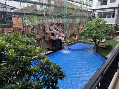 a swimming pool with a waterfall in a building at Green Garden Hotel in Kuta