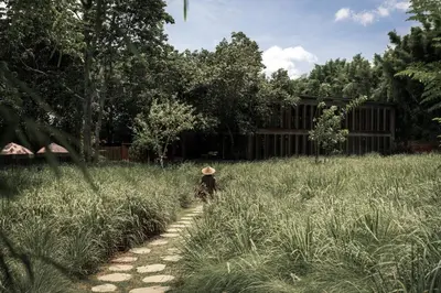 a person with a hat walking through a field at Balquisse Heritage Hotel in Jimbaran