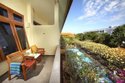 a balcony with chairs and a view of a garden at Febri's Hotel & Spa in Kuta