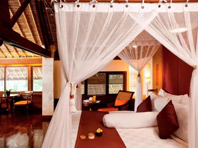 a bedroom with a bed with curtains and a living room at The Royal Beach Seminyak Bali in Seminyak