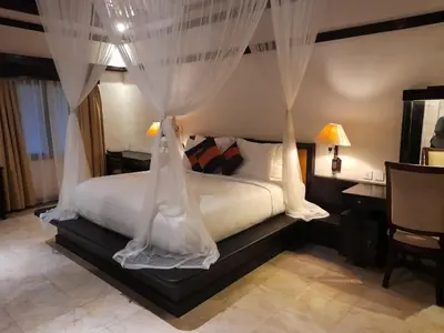 a bedroom with a bed with curtains and a desk at The Royal Beach Seminyak Bali in Seminyak