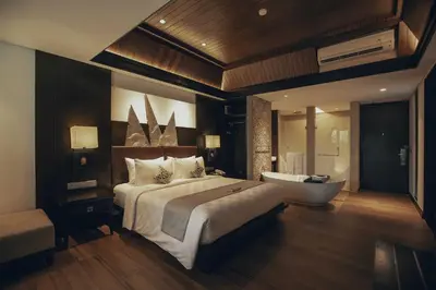 a bedroom with a large bed and a tub in a room at The Vira Bali Boutique Hotel & Suite in Kuta