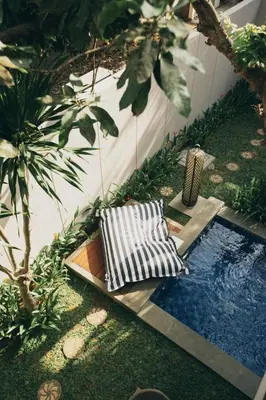 a garden with two chairs and a swimming pool at The Vira Bali Boutique Hotel & Suite in Kuta