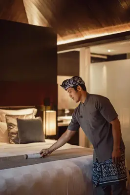 a man is standing next to a bed at The Vira Bali Boutique Hotel & Suite in Kuta