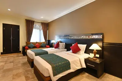a hotel room with two beds and a couch at Puri Dewa Bharata Hotel & Villas in Legian