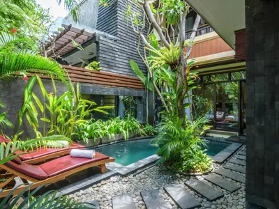 a swimming pool in a garden with a bench at The Bali Dream Villa Seminyak in Seminyak