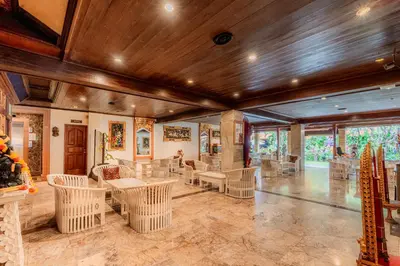 a room with white chairs and tables and windows at Wina Holiday Villa Kuta Bali in Kuta
