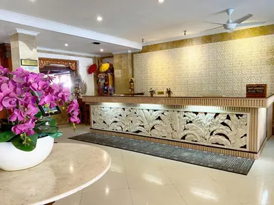 a lobby with a counter with purple flowers in a vase at Wina Holiday Villa Kuta Bali in Kuta