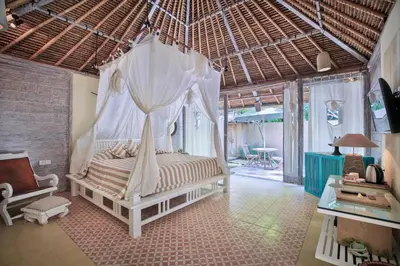 a bedroom with a bed with a mosquito net at Visakha Sanur by Puri Signatures in Sanur