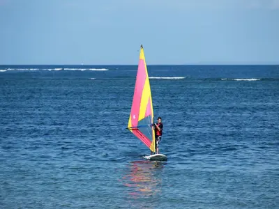 a man is windsurfing on the water with a sail at Grand Mirage Resort & Thalasso Bali in Nusa Dua