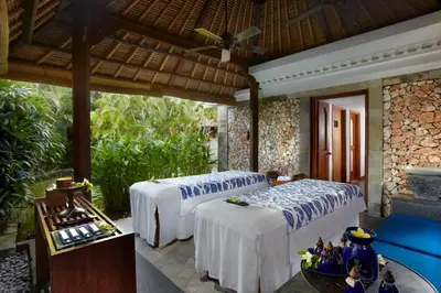 a bedroom with two beds and a table with a table at The Oberoi Beach Resort, Bali in Seminyak