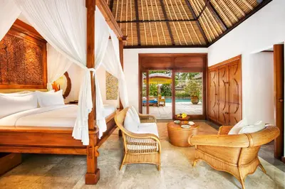 a bedroom with a bed and two chairs at The Oberoi Beach Resort, Bali in Seminyak