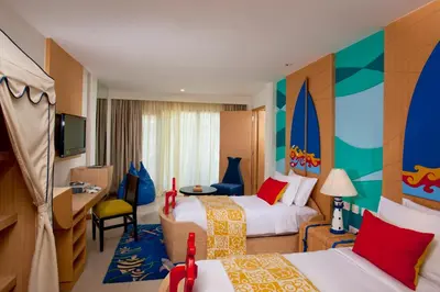 a hotel room with two beds and a tv at Holiday Inn Resort Baruna Bali by IHG in Kuta