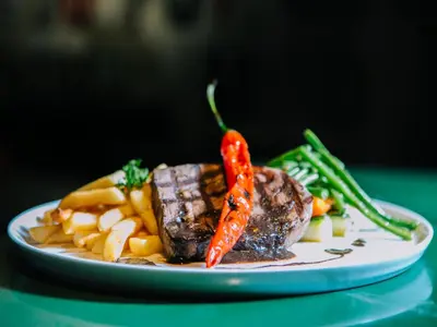 a plate of steak and vegetables on a table at FuramaXclusive Ocean Beach Seminyak Bali in Legian