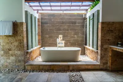 a bath tub in a bathroom with a brick wall at Bali Prime Villas Seminyak by Kanaya Hospitality in Seminyak