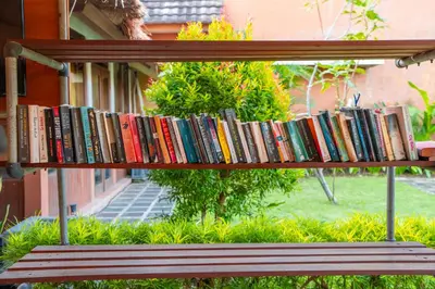 a shelf of books sitting on top of a bench at Desamuda Village by Pertama Management in Seminyak
