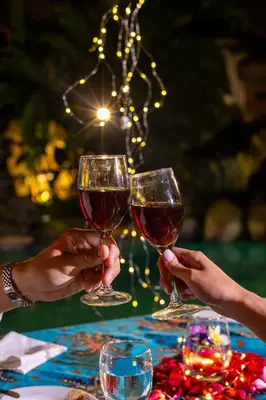 two people holding glasses of wine on a table at Desamuda Village by Pertama Management in Seminyak