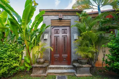 a house with a red door and some plants at Desamuda Village by Pertama Management in Seminyak
