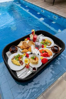 a tray of food sitting next to a swimming pool at Desamuda Village by Pertama Management in Seminyak