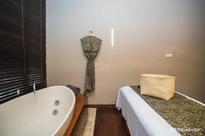 a bathroom with a tub and a dress hanging on the wall at The Elysian Boutique Villa Hotel in Seminyak