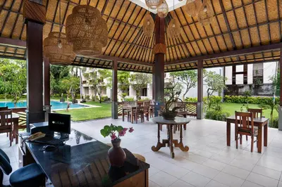 a pavilion with a table and chairs and a pool at Kusuma Resort Seminyak in Seminyak