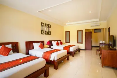a hotel room with two beds and a desk at Kusuma Resort Seminyak in Seminyak