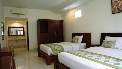 a hotel room with two beds and a mirror at Kusuma Resort Seminyak in Seminyak