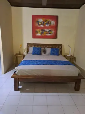 a bedroom with a large bed with blue pillows at Shalana Homestay- formerly Teka Teki House in Seminyak