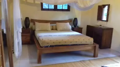 a bedroom with a bed and a wooden bed frame at Shalana Homestay- formerly Teka Teki House in Seminyak