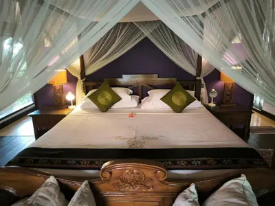 a bedroom with a large bed with a canopy at Umah Watu Villas in Seminyak