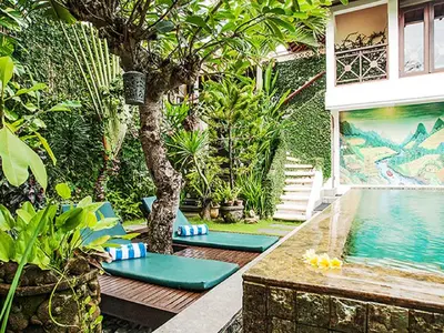 a garden with a pool and a tree and a house at Umah Watu Villas in Seminyak
