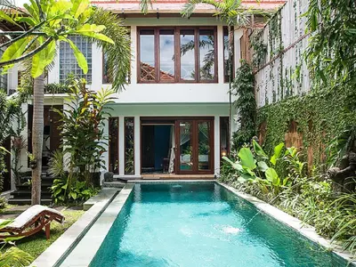 a house with a swimming pool in front of a house at Umah Watu Villas in Seminyak