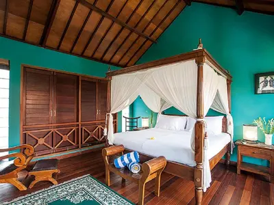 a bedroom with a canopy bed and green walls at Umah Watu Villas in Seminyak