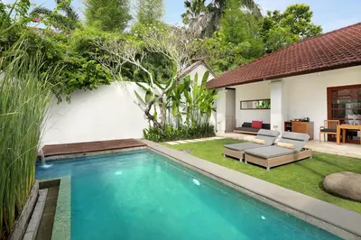 a swimming pool in a backyard with a couch and a table at Uma Sapna Seminyak in Seminyak