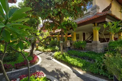 a garden in front of a building with trees and flowers at Royal Hotel and Villa Bali in Legian